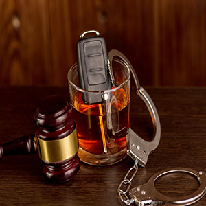 DUI Attorney: Glass of whiskey, car keys, handcuffs, and a judge's gavel representing DUI defense services.
