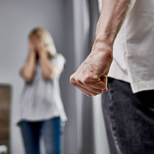 Domestic Violence: Silhouette of a distressed woman with a man's clenched fist in the foreground for legal help.