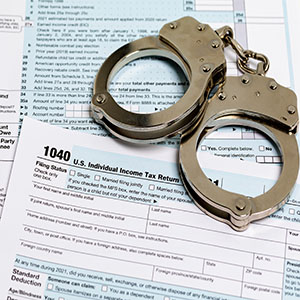 Alt Text: Handcuffs resting on a 1040 U.S. tax form, representing federal crimes and financial fraud.