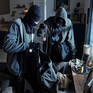 Grand Theft: Two masked individuals in hoodies stealing jewelry and items from a home during a burglary.