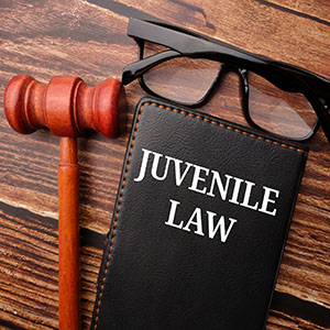Juvenile Crimes: A "Juvenile Law" book, eyeglasses, and a gavel on a wooden desk.
