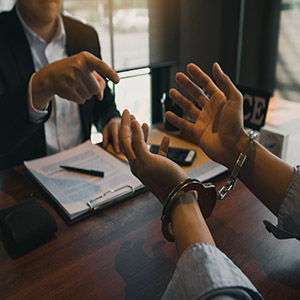 Person in handcuffs sitting across from a legal professional during a consultation.