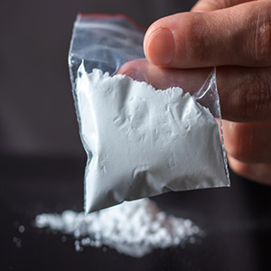 Hand holding a small plastic bag of white powder, illustrating legal challenges regarding intent in Florida drug cases.