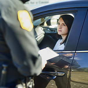 Police officer speaking to a witness through a car window during a criminal investigation.