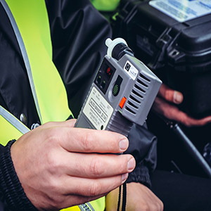 Close-up of a driver blowing into a breathalyzer device during a Florida sobriety checkpoint.