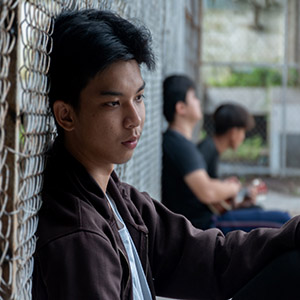 Young man looking out of a window, representing juveniles direct-filed into adult court.