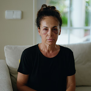 Distressed woman sitting on a couch, representing the serious nature of domestic violence allegations.
