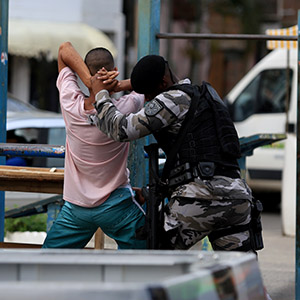 Law enforcement officer in tactical gear detaining a suspect during a drug raid in South Florida.