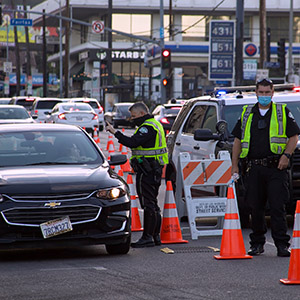 Police officers managing a nighttime DUI sobriety checkpoint with orange cones and patrol cars.