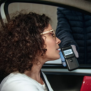 Woman performing a roadside breathalyzer test during a DUI traffic stop.