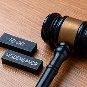 Courtroom gavel with Felony and Misdemeanor blocks representing criminal charge classifications.